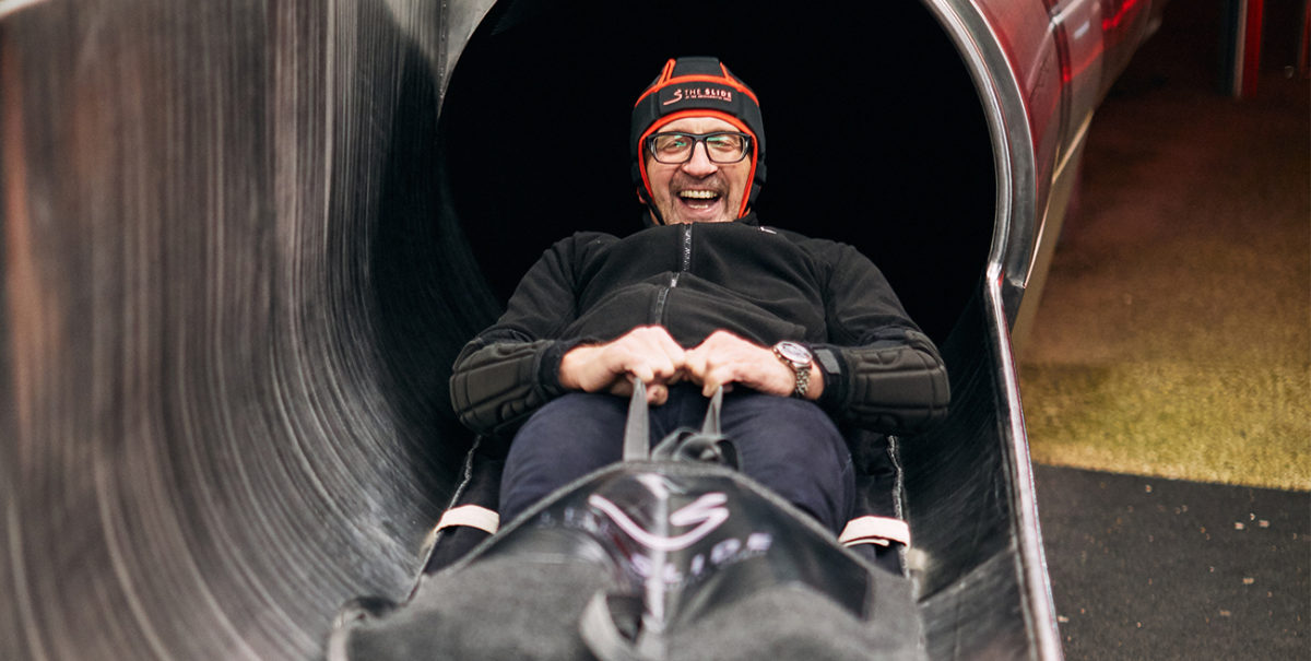 Smiling man coming down a slide